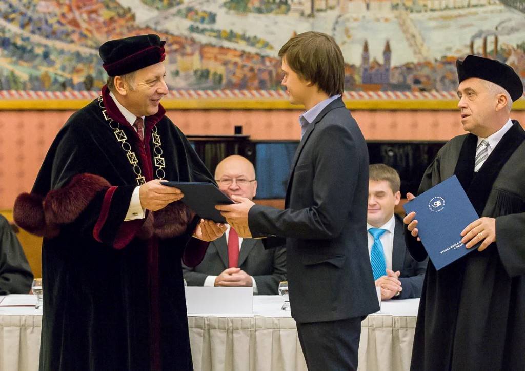 Student přebírá diplom z rukou rektora při promoci
